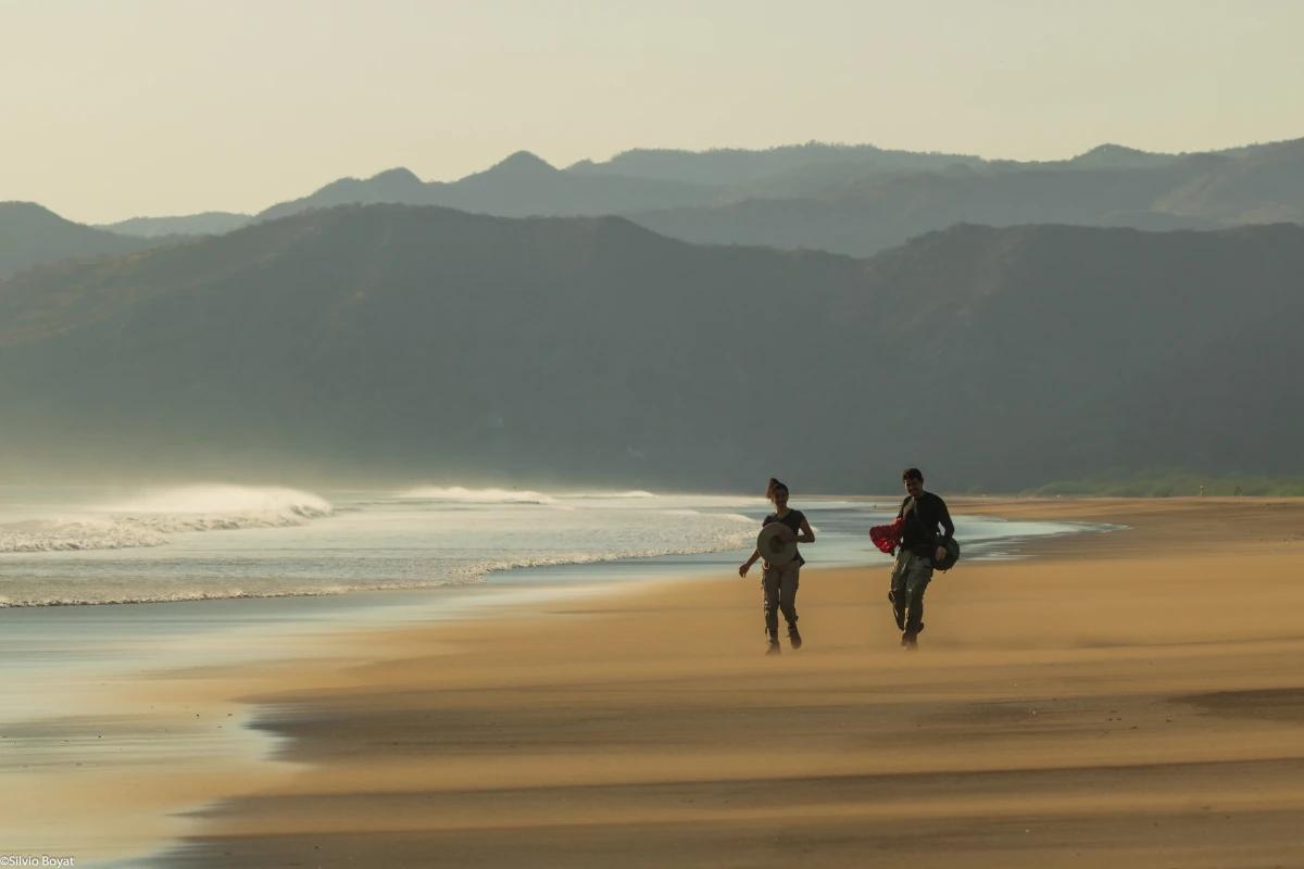 Deux voyageurs marchent dans le vent balayant la plage sauvage Naranjo du Parc National Santa Rosa